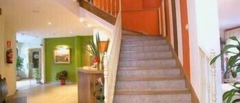 A staircase with a wooden handrail and beige steps leading to a landing with a green wall and a framed picture.
