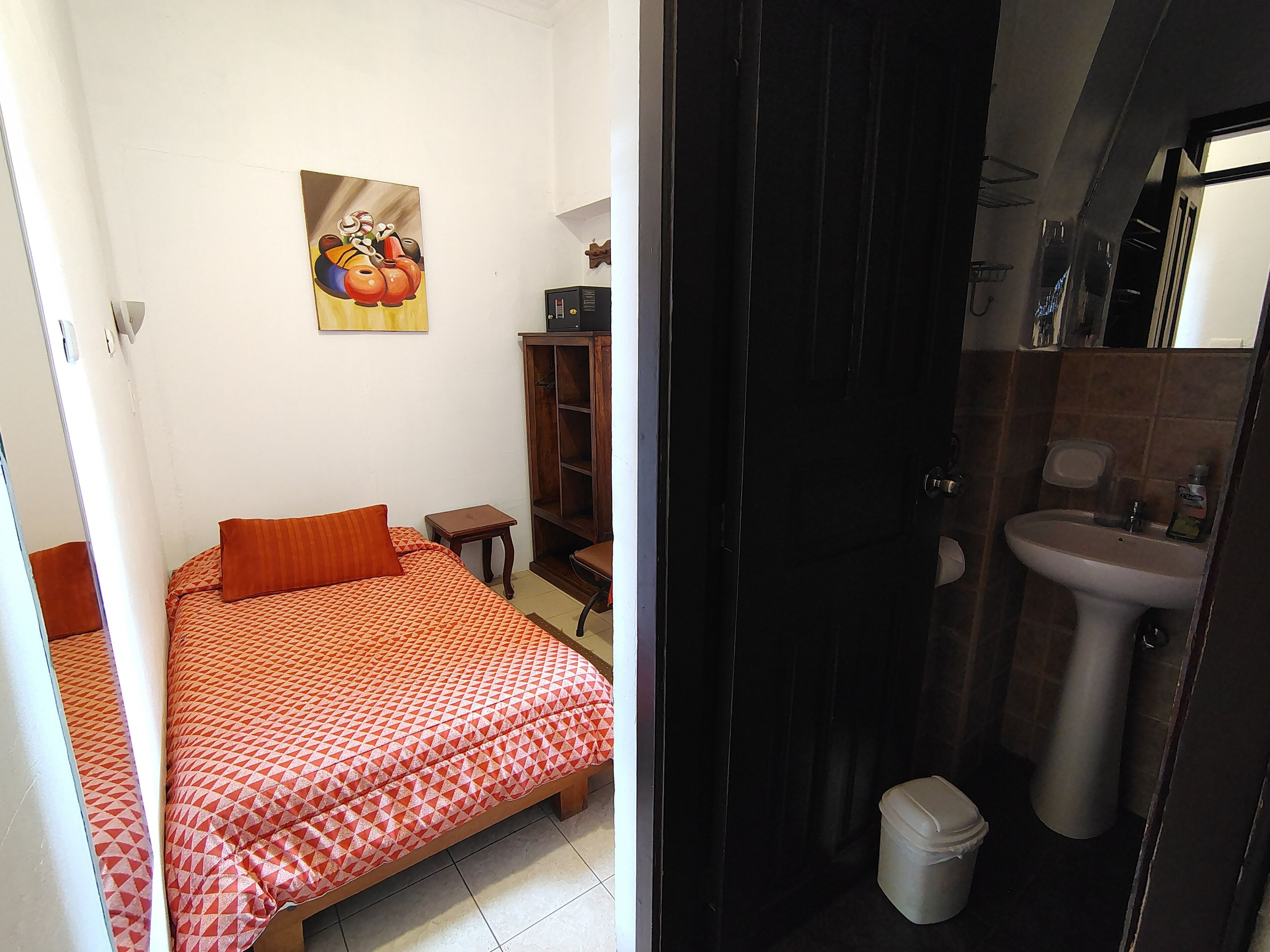 Un dormitorio con cama, una mesita, un armario y un cuadro en la pared.