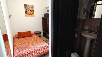 Un dormitorio con cama, una mesita, un armario y un cuadro en la pared.