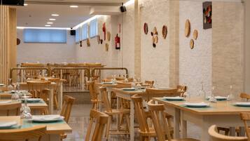 A spacious dining area with multiple wooden tables and chairs, arranged in a casual layout.