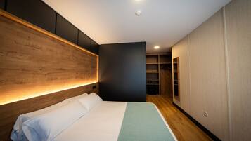 A modern hotel room with a wooden headboard, a large bed, and built-in wardrobes.