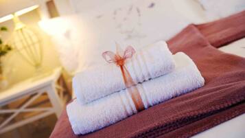 A stack of neatly folded towels tied with a ribbon, placed on a brown towel on a white surface.