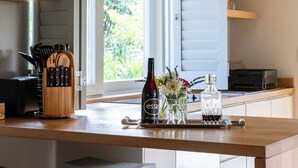 Une cuisine moderne avec un îlot central en bois, des tabourets de bar et une vue sur la verdure environnante.