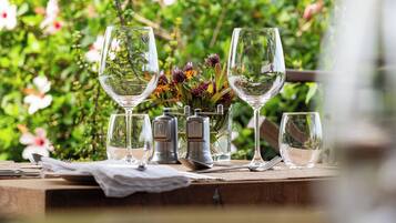 A table set outdoors with wine glasses and a vase of flowers.