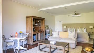 A living room with a sofa, a coffee table, a dining table with chairs, and a kitchen area with cabinets.