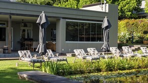 Un bâtiment moderne doté d’une piscine, de chaises longues et de parasols.