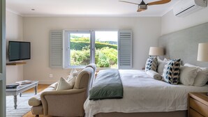Une chambre à coucher avec un lit, une chaise, une télévision et une fenêtre avec des volets.