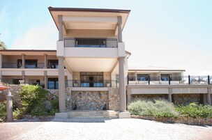 Un hotel de varios pisos con fachada de piedra, balcones y un área de entrada cubierta.