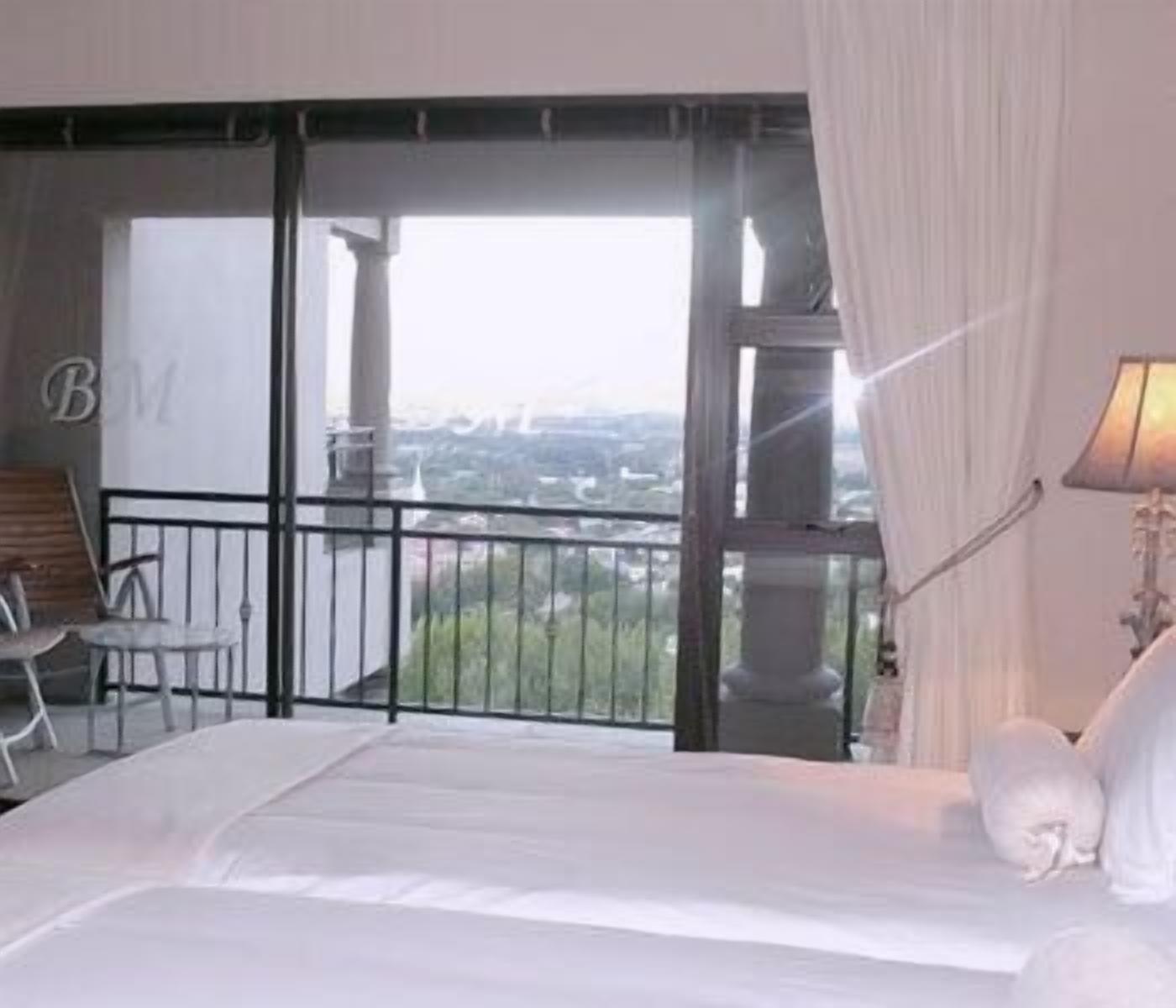 Una habitación de hotel con balcón, una cama, una silla y una lámpara.