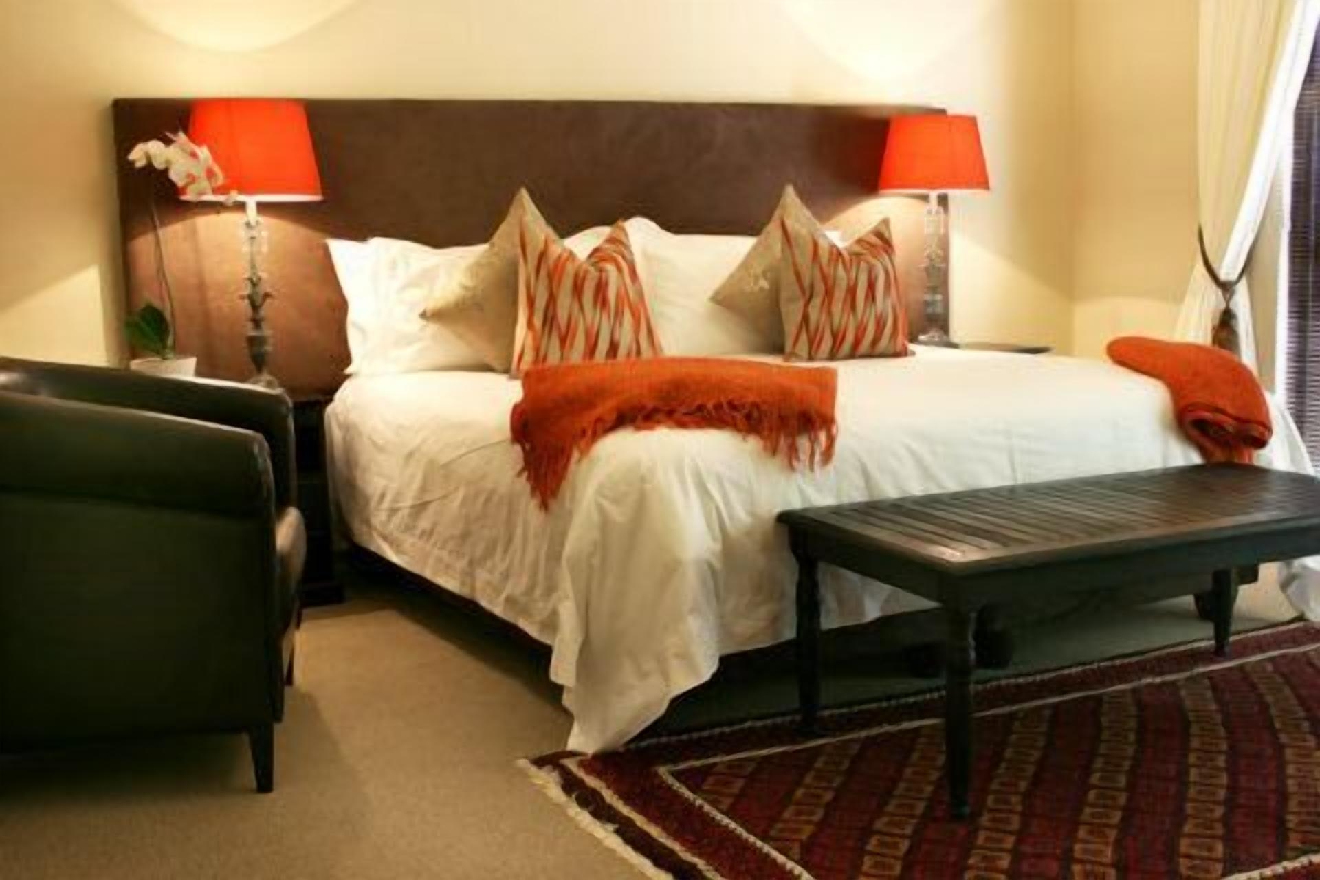 A neatly arranged bedroom with a bed, two bedside tables, a nightstand, and a red patterned rug.