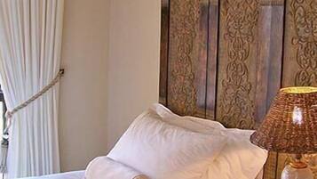 Una cama con sábanas blancas impecables, cabecero de madera con intrincados grabados y una lámpara de noche de estilo clásico.