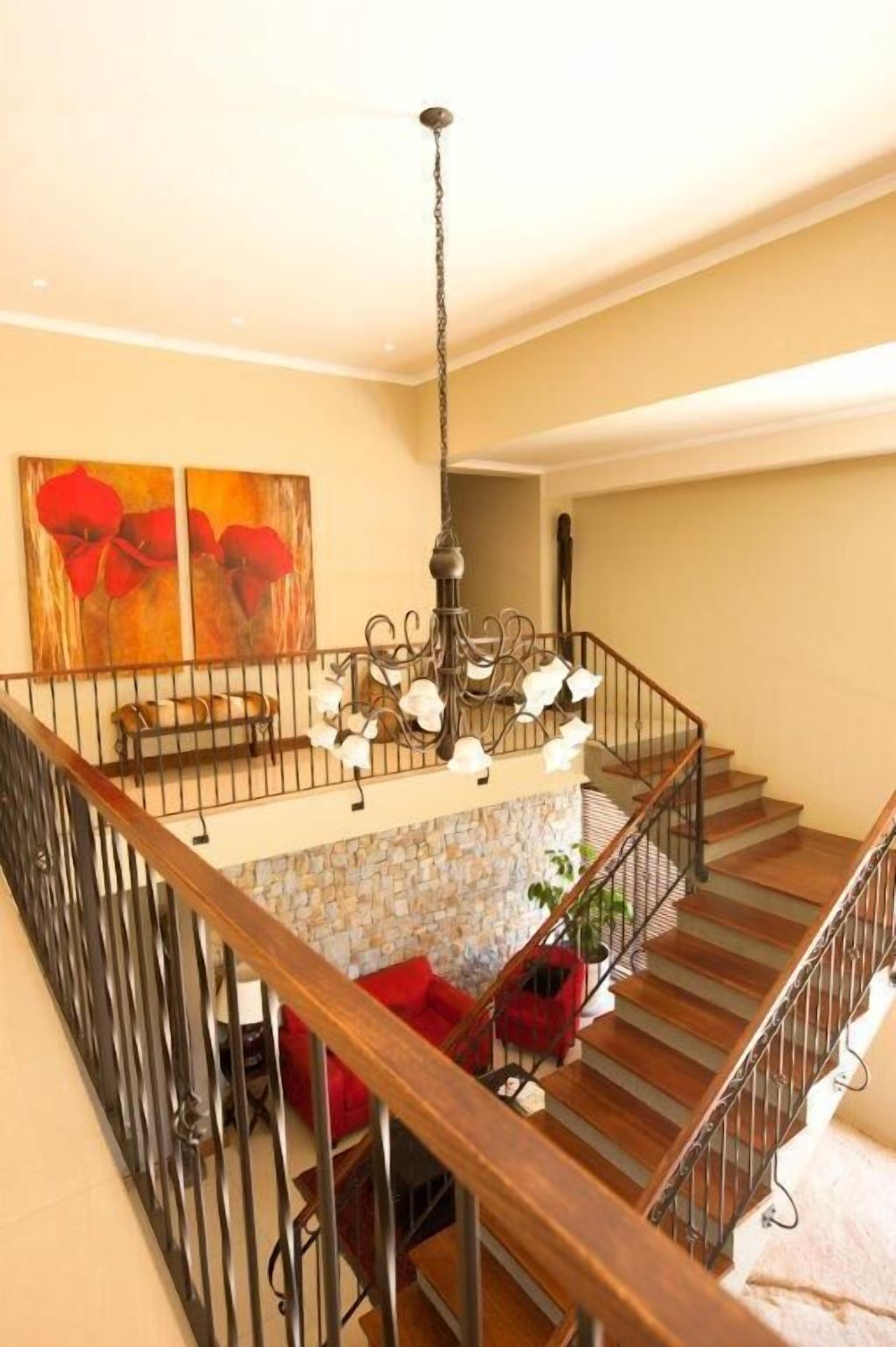 Una escalera con pared de piedra, barandilla metálica y un candelabro.