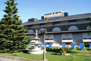 A hotel with a sign, a fountain, and blue lounge chairs. - Sandra II (Suances)