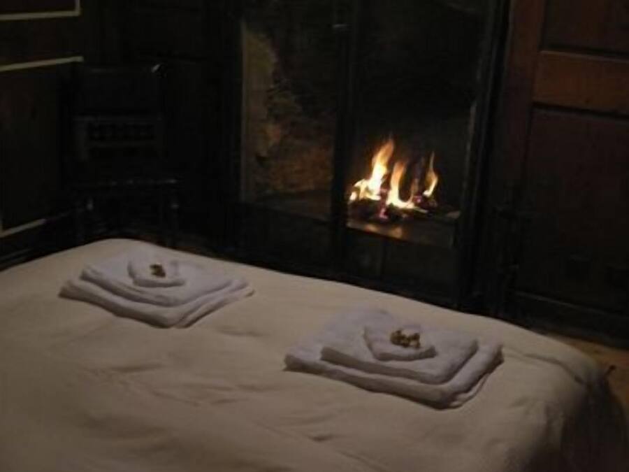 A hotel room with a fireplace, a bed with towels, and a nightstand.