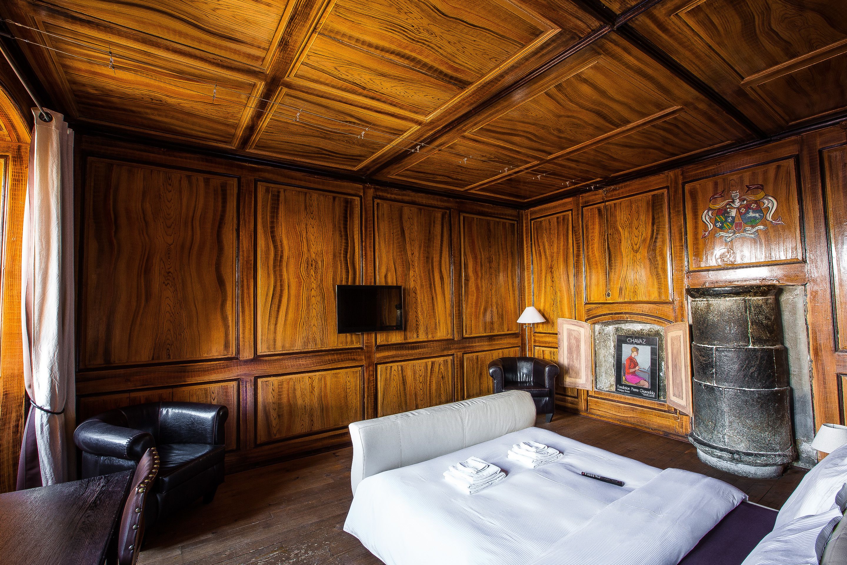 Ein Zimmer mit Holzwänden, einem Kamin, einem Bett, einem Schreibtisch und einem Stuhl.
