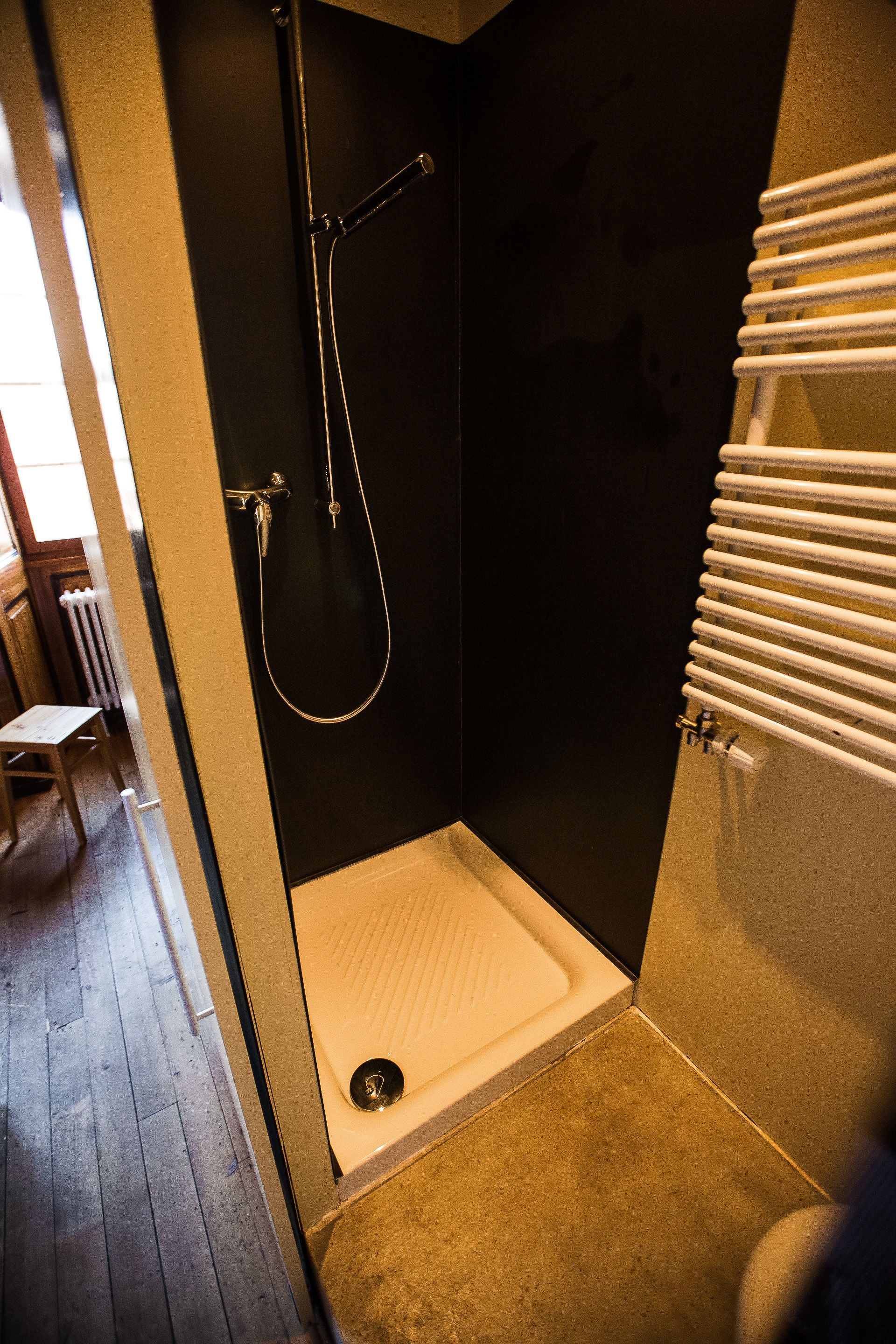 Un bagno piccolo con pareti scure, dotato di doccia, WC e termosifone.