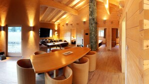Un interior espacioso de madera con una mesa de comedor curva, asientos acolchados y un pilar de piedra.