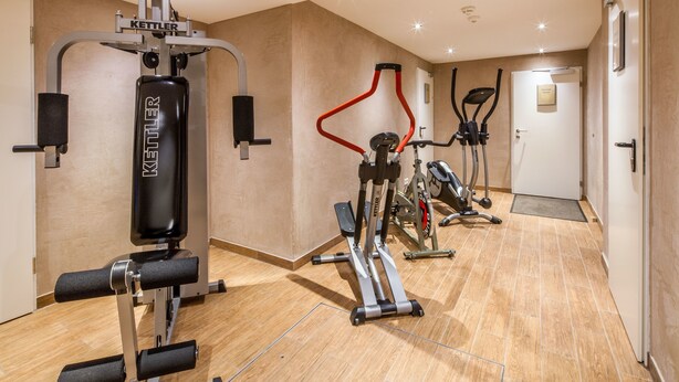A gym with various exercise machines, including a Kettler machine, a red elliptical, and a stationary bike. - Gasthaus - Pension Reiterklause (Leutasch)