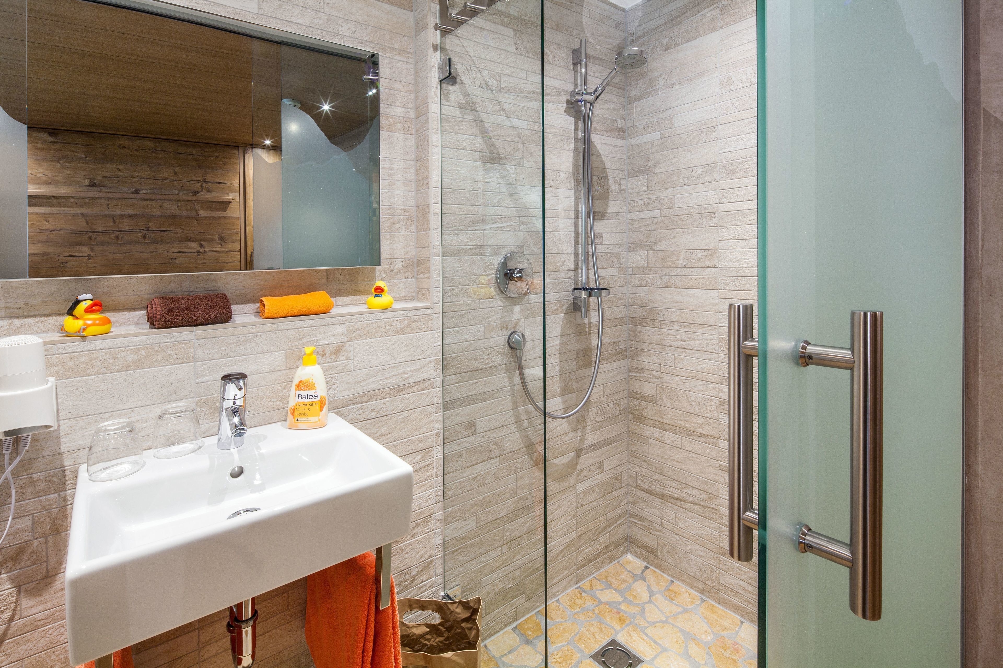 Un baño moderno con cabina de ducha de vidrio, un lavabo blanco y un espejo encima.
