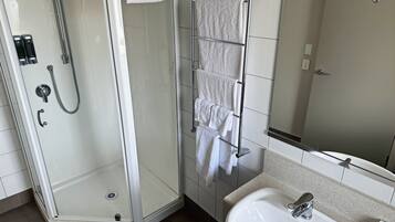 A modern bathroom with a glass-enclosed shower, a towel rack with multiple towels, a sink, and a mirror.