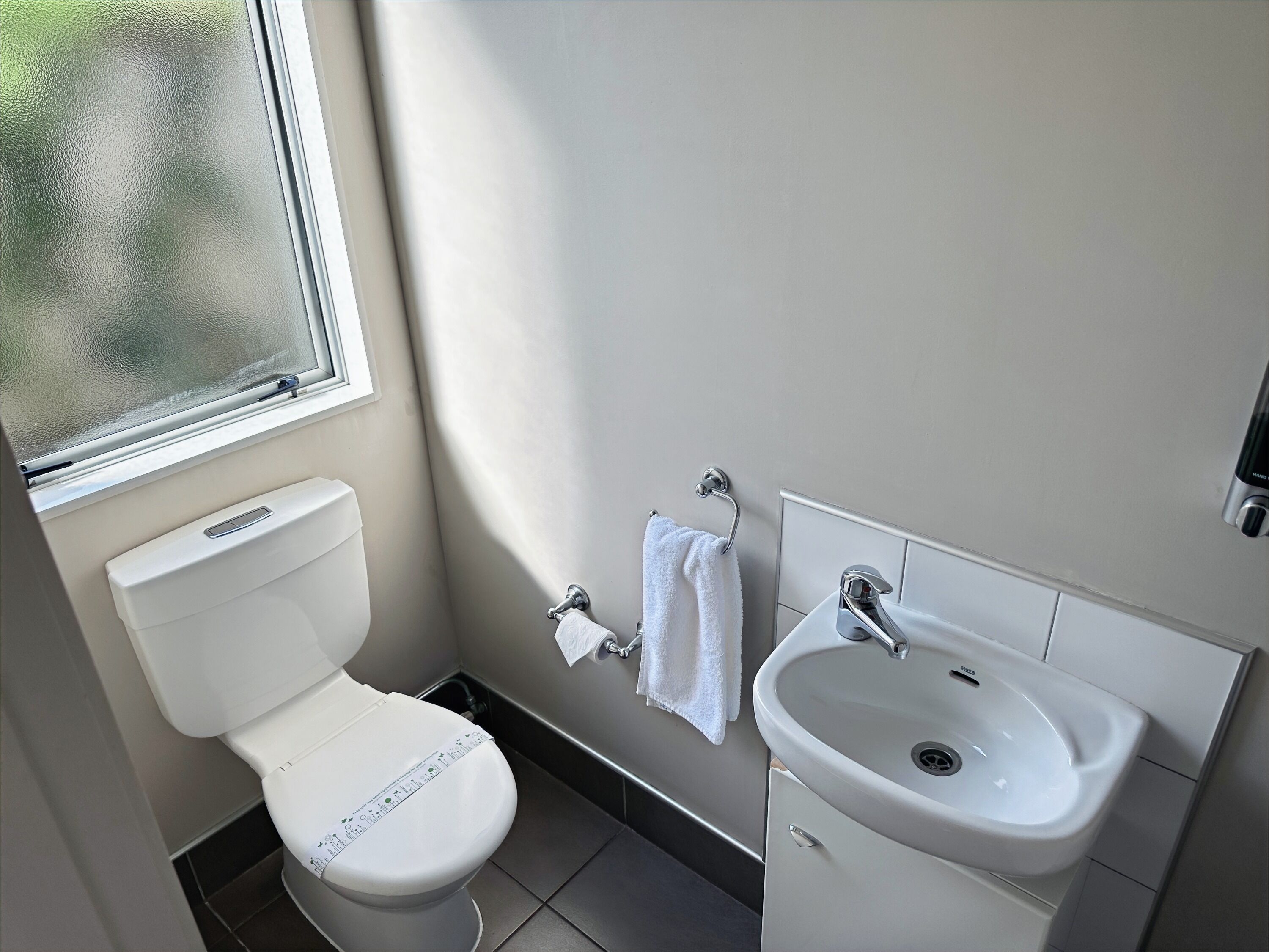 A modern bathroom with a toilet, sink, and window.