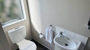 A modern bathroom with a toilet, sink, and window.