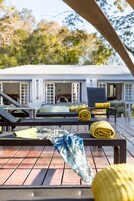 Una piscina al aire libre, sombrillas, sillones reclinables de piscina