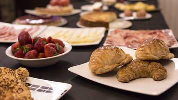 Una mesa de buffet con diversos alimentos, incluyendo croissants, fresas y otras pastas.