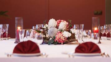 A table set for a formal dining occasion with a centerpiece of flowers and candles.