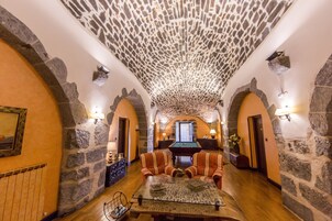 Una habitación con paredes de piedra, mesa de billar, sillones a rayas y mesa de billar.