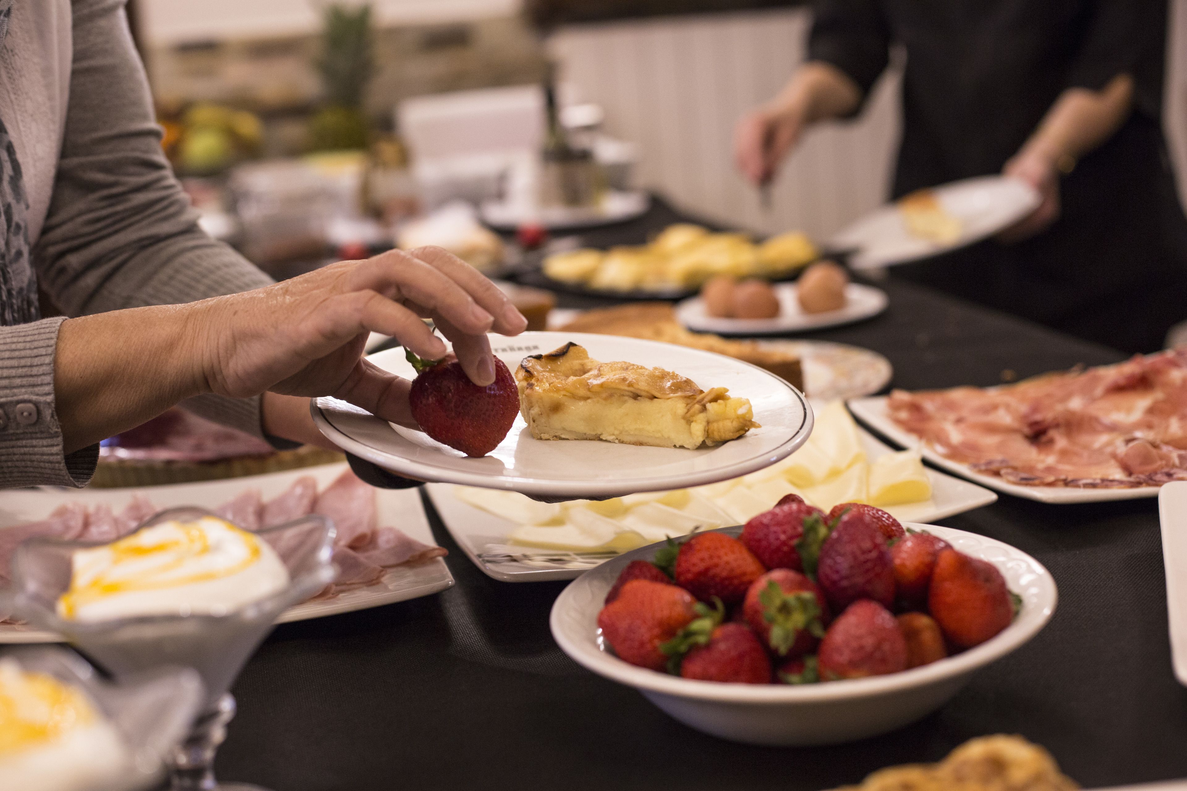 Una mesa de comedor con diversos alimentos, incluyendo fresas, una porción de pastel y platos de comida.
