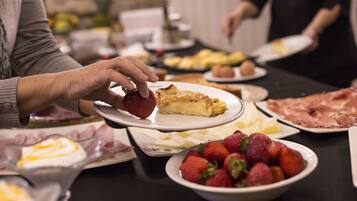 Una mesa de comedor con diversos alimentos, incluyendo fresas, una porción de pastel y platos de comida.