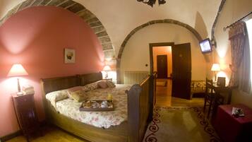 A bedroom with a bed, bedside lamps, a television, a desk, and a chair.