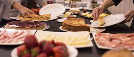 Una mesa de buffet con diversos alimentos, incluyendo carnes, quesos y frutas.