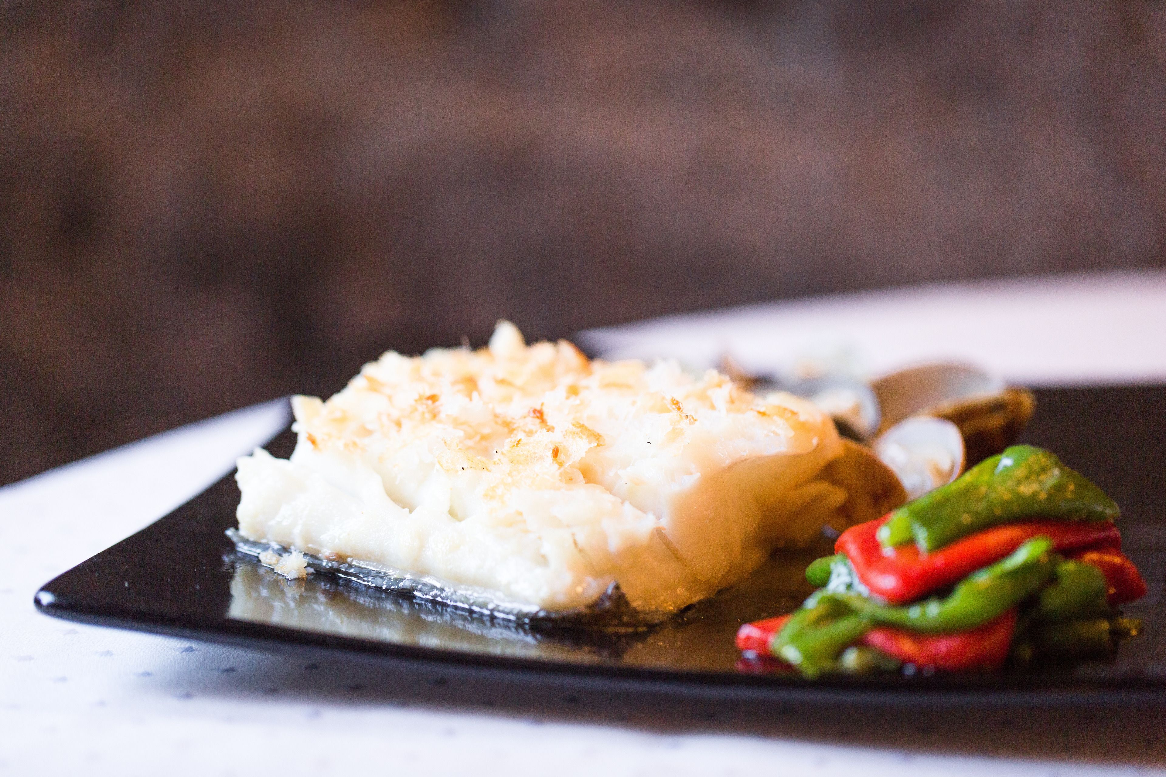 A plate with a piece of white food, possibly fish, and some green vegetables.