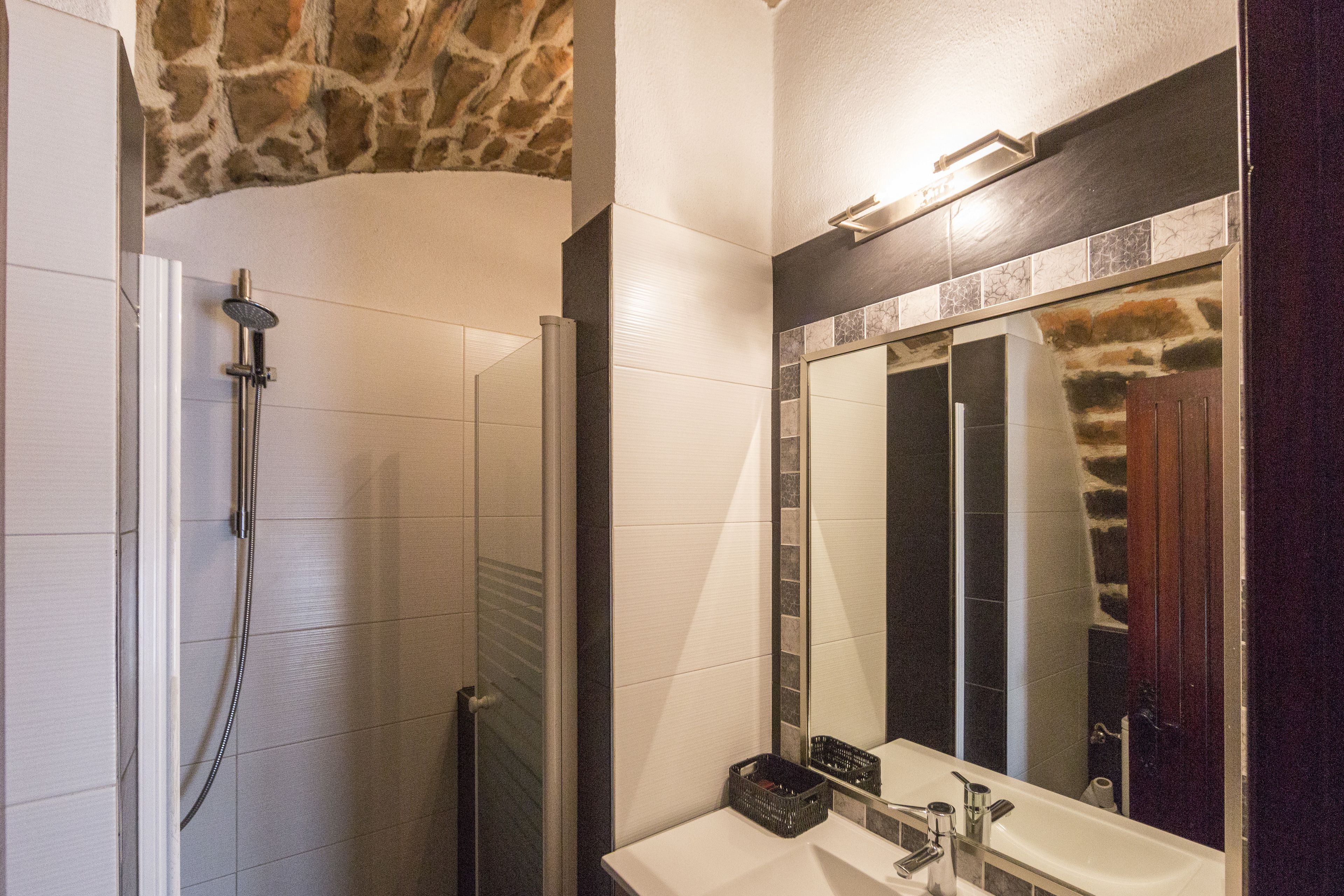 A bathroom with a shower, a sink, and a large mirror.