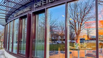 Ein modernes Gebäude mit großen Fenstern und einem Schild mit der Aufschrift 'RESTAURANTE CAFETERIA'.
