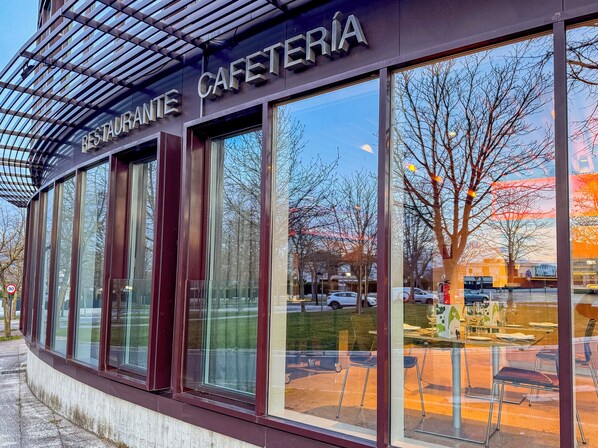 A modern building with large windows and a sign reading "RESTAURANTE CAFETERIA". - Jardines de Uleta Suites (Vitoria-Gasteiz)