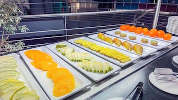A buffet with various fruits and vegetables arranged on white trays.