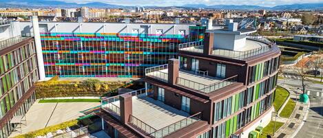 Un edificio moderno con estructura de varios pisos, ventanas amplias y una terraza en la azotea.
