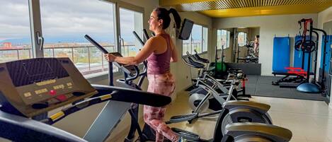 Un gimnasio con cintas de correr, bicicletas estáticas y máquinas de pesas.