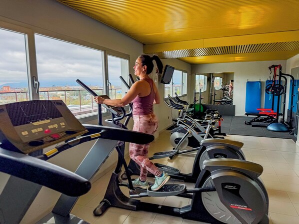 Un gimnasio con cintas de correr, bicicletas estáticas y máquinas de pesas.