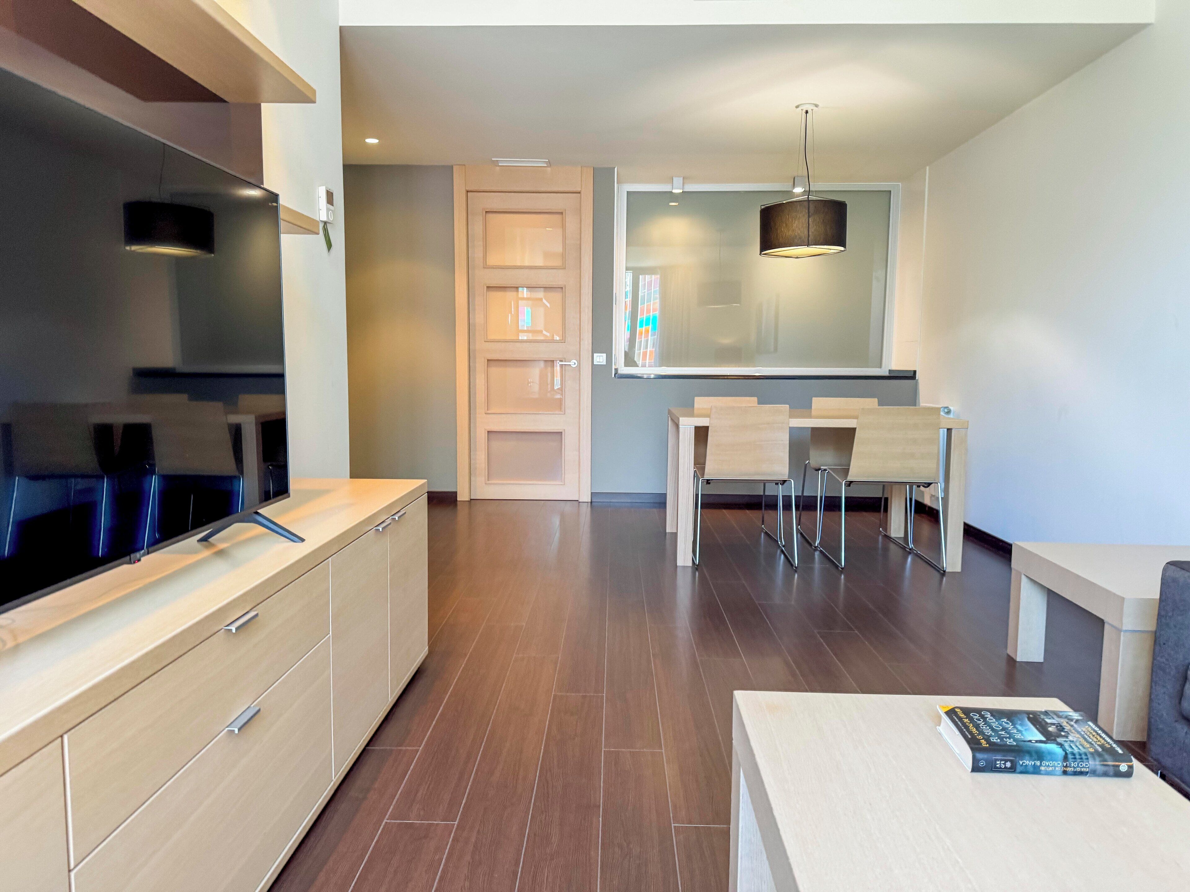 Eine moderne Küche mit Backofen, ein Essbereich mit Tisch und Stühlen sowie ein großes Fenster.