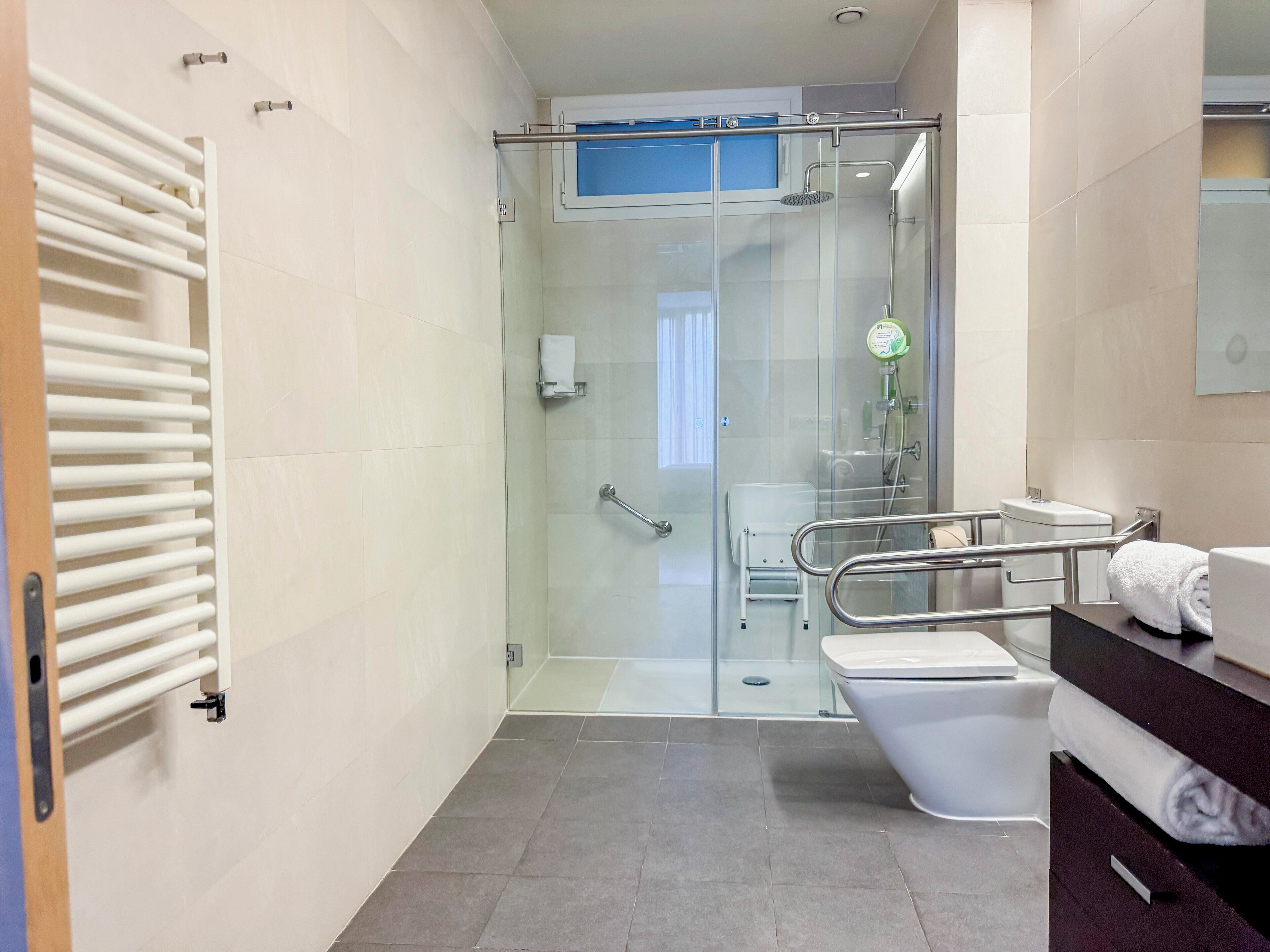 Ein modernes Badezimmer mit einer Glaskabine zur Dusche, einer weißen Toilette und einem Handtuchhalter.