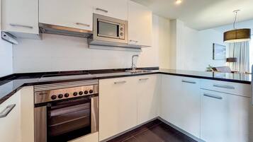 Een moderne keuken met witte kasten, een inbouwoven, een magnetron en een roestvrijstalen afzuigkap.