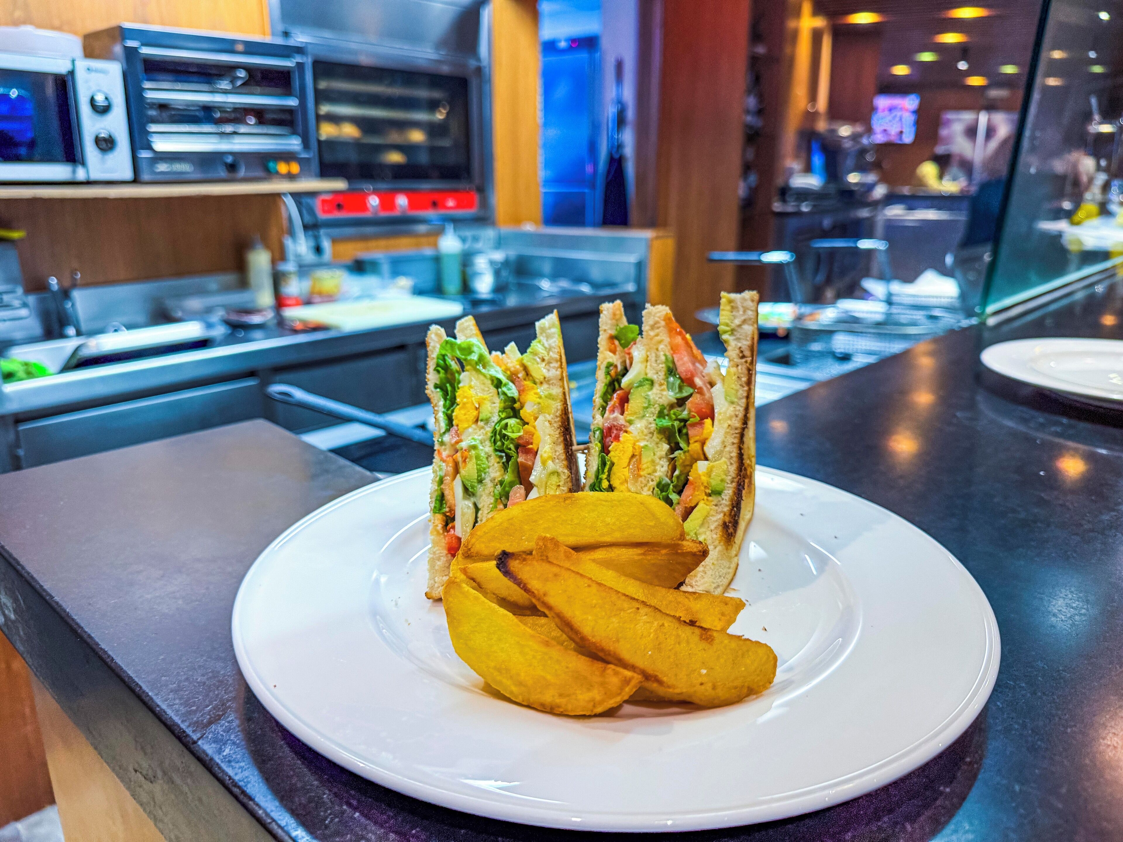 A plate with a sandwich and fries on a counter in a restaurant.