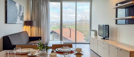 A modern dining area with a large window offering a view of buildings and greenery.