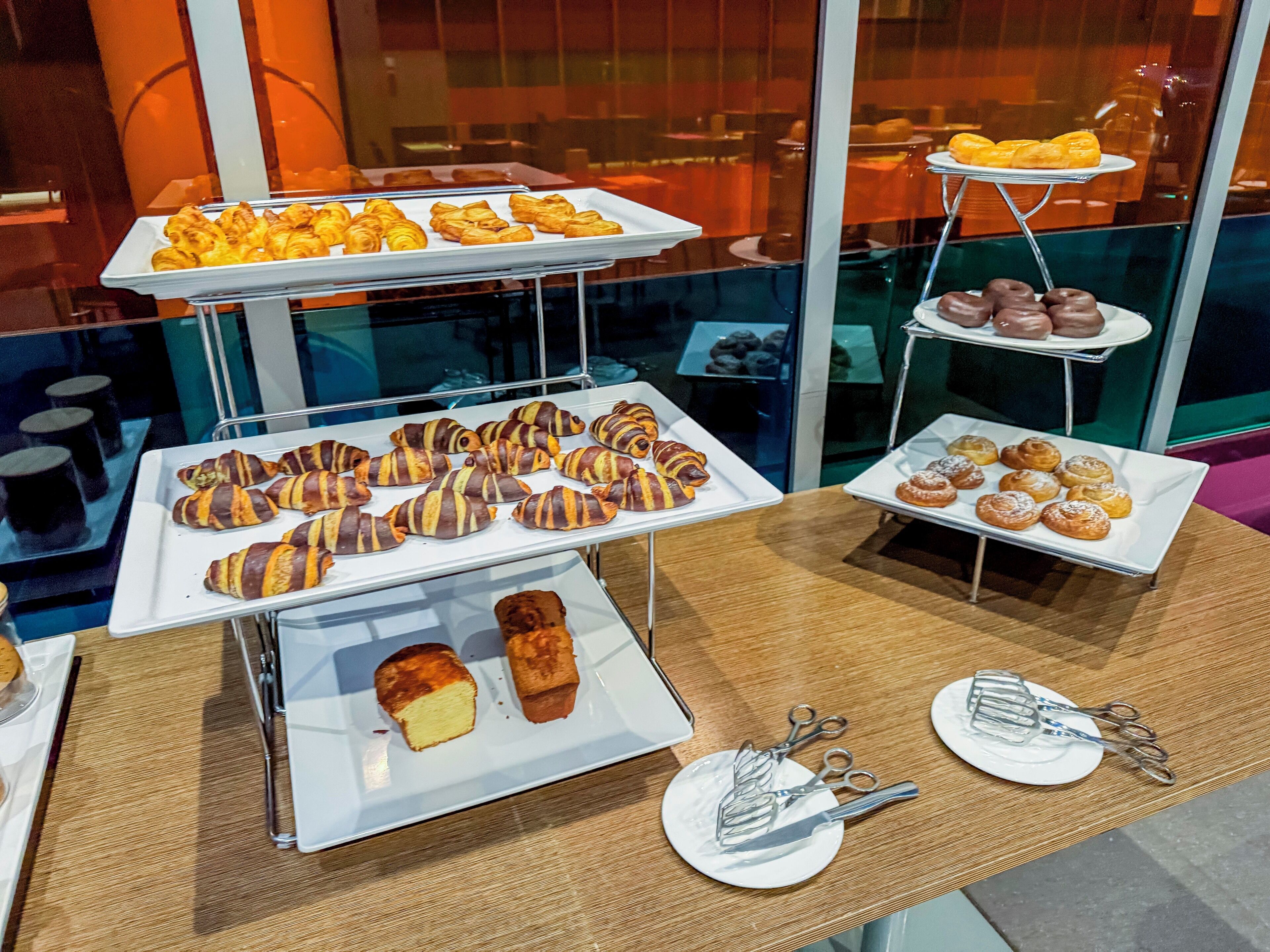 A buffet with various pastries and desserts displayed on white trays.