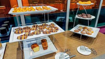 A buffet with various pastries and desserts displayed on white trays.