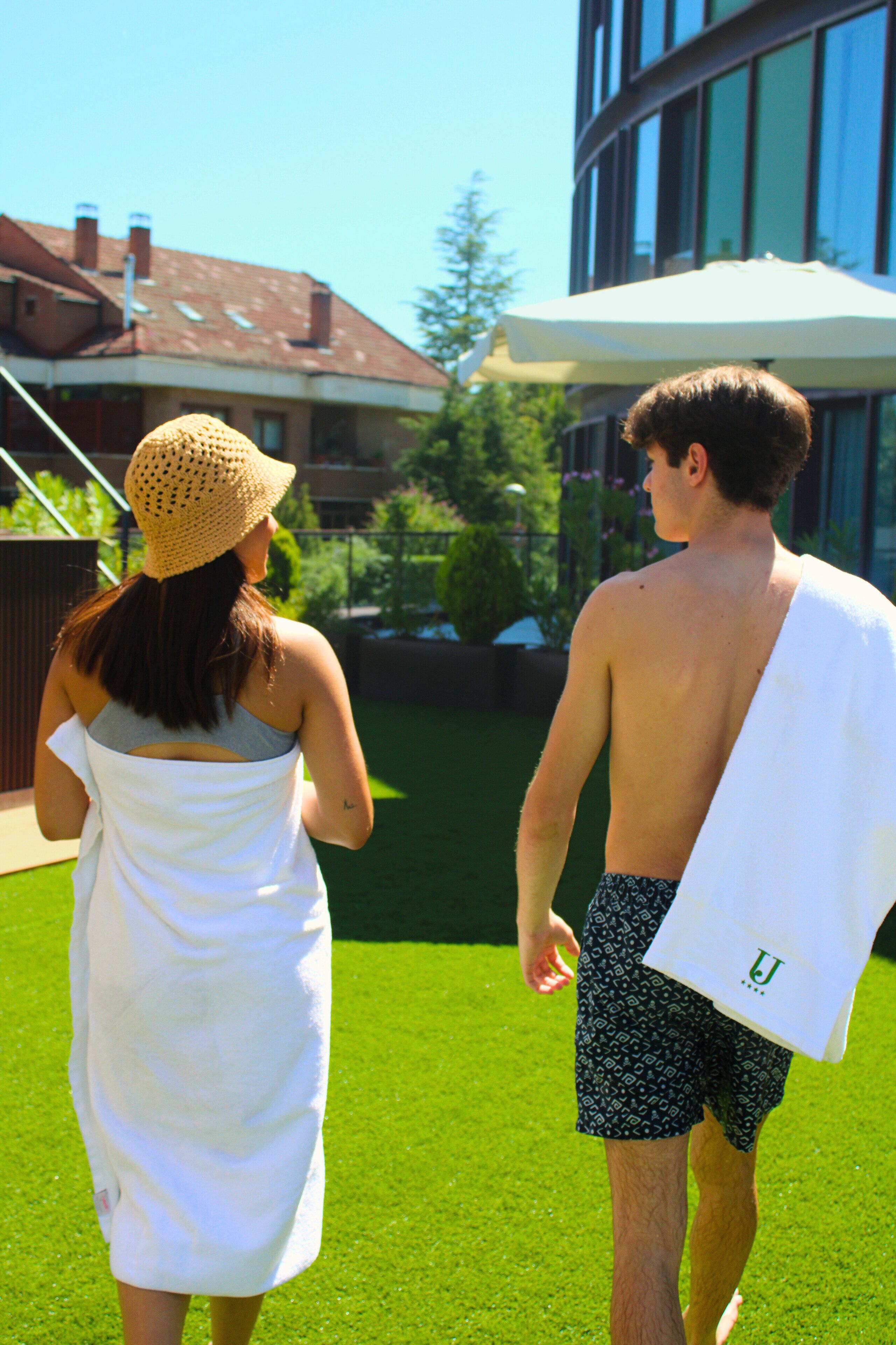 A man and a woman walking on a grassy lawn with a building in the background.